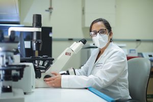 Dr. Ritu Chakravarti sits behind a microscope